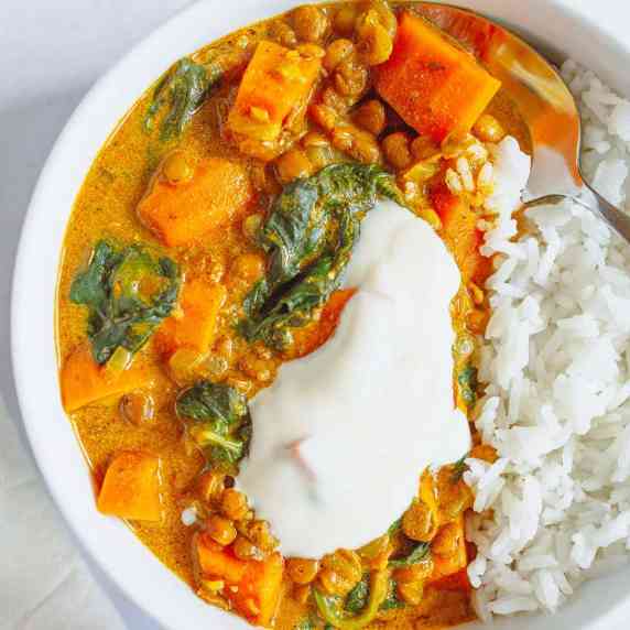 sweet potato and lentil curry with rice and spoon in a white bowl, a white kitchen towel 