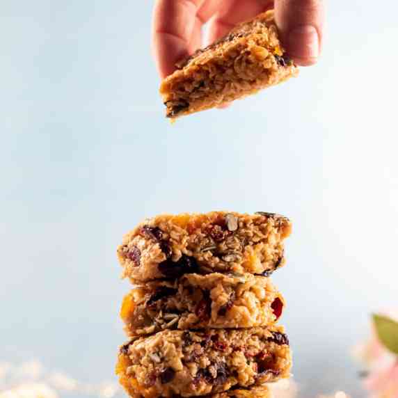 A hand lifting the top flapjack from a stack of them. 