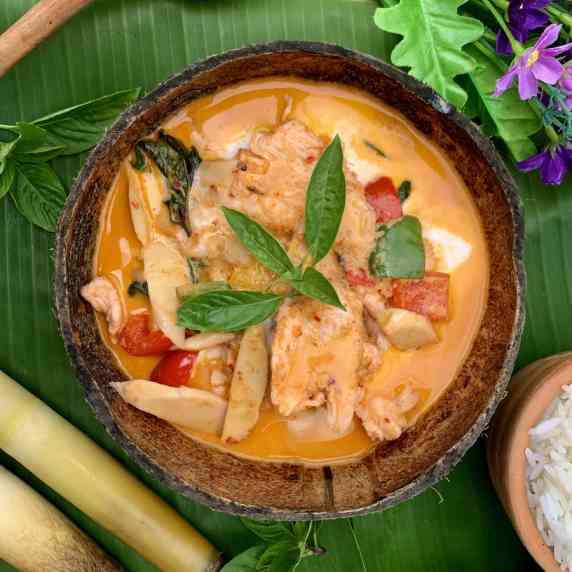 Thai red curry chicken - gaeng daeng - in a coconut shell with bamboo shoots and vegetables.