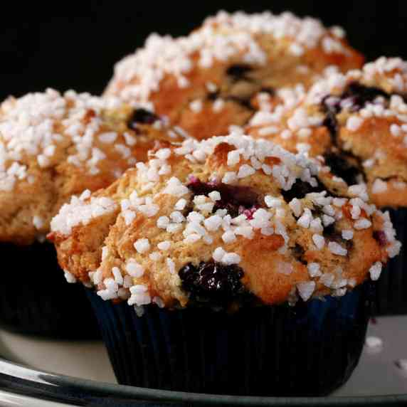 Several sugar topped gluten free blueberry muffins on a plate.