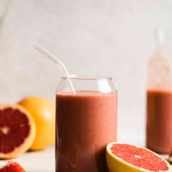 Grapefruit smoothie arranged in an aesthetic glass with straw and a grapefruit on the side