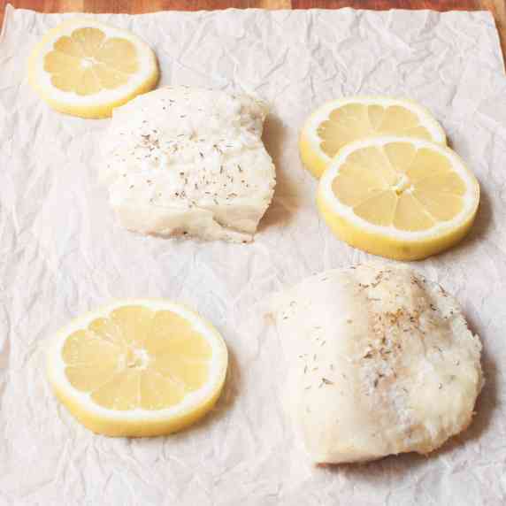 Cod fillets with lemon slices on parchment paper