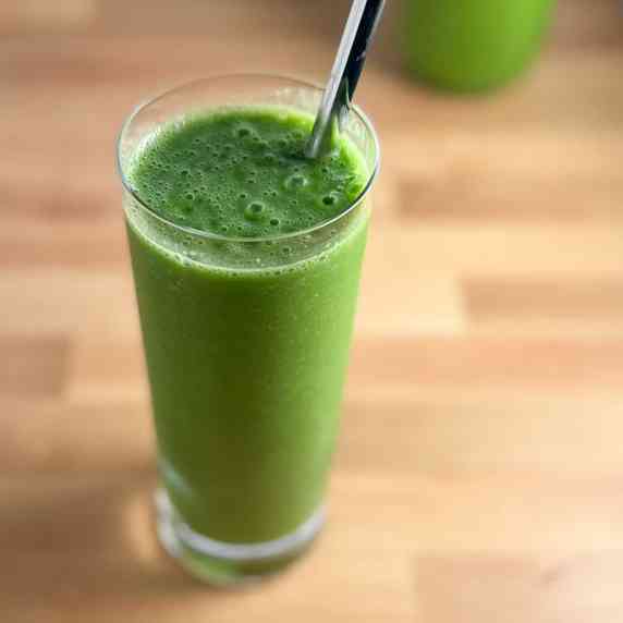 top side view of green smoothie in tall glass with metal straw