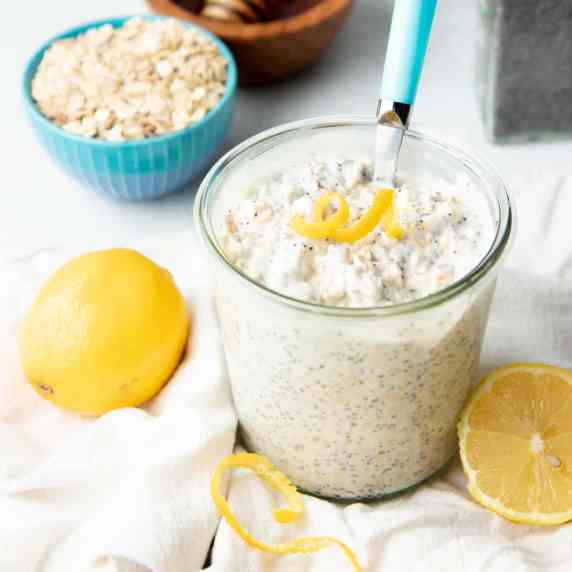 A spoon tucks into a jar of lemon poppyseed overnight oats garnished with a lemon twist.