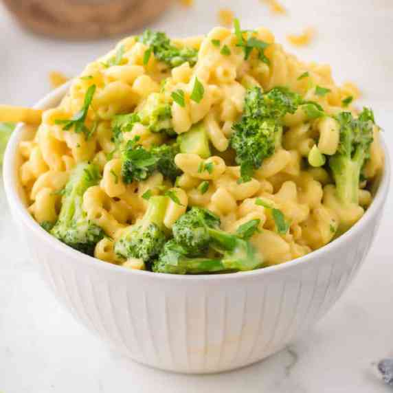 Mac and cheese with broccoli garnished with fresh parsley in a bowl from the side.