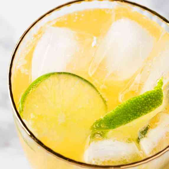 A mango mojito mocktail garnished with lime wheels.
