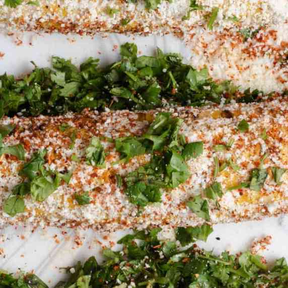 A platter of Mexican street corn with Tajin, cotija, cilantro, and mayonnaise. 