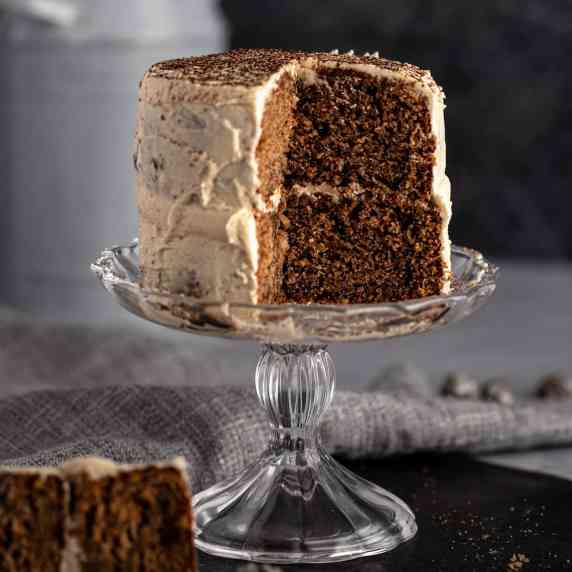 A chocolate mini layer cake sitting on a small glass cake stand. 