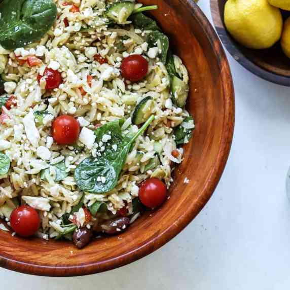 large wooden bowl full of greek orzo pasta salad