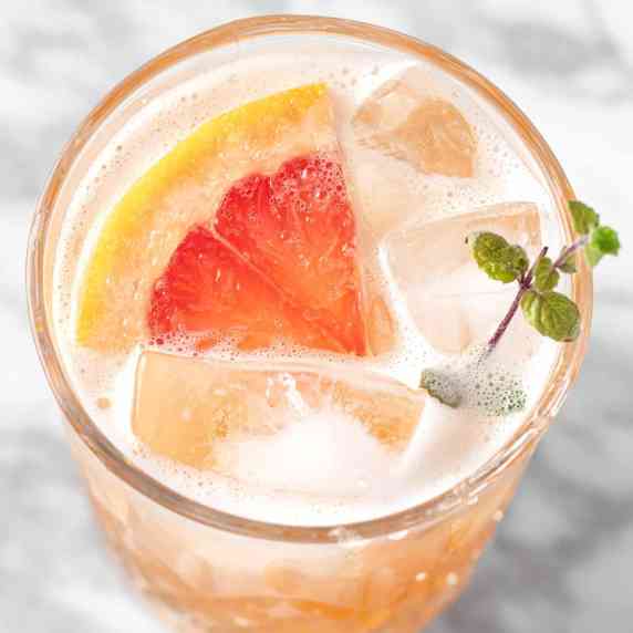 A paloma mocktail garnished with a slice of grapefruit and sprig of mint.