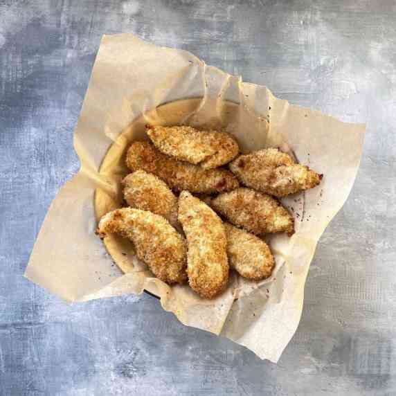 bowl of crispy chicken tenders in parchment paper.