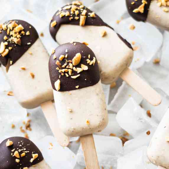 Peanut butter banana popsicles decorated with chocolate glaze and chopped peanuts
