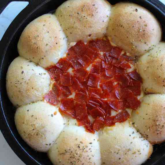 Cast iron skillet pepperoni pizza dip with rolls.