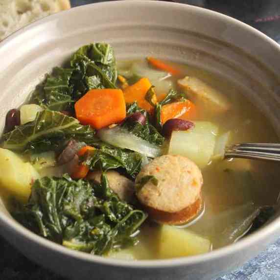 portuguese kale soup in bowol, with sausage, carrots and kale near the top.
