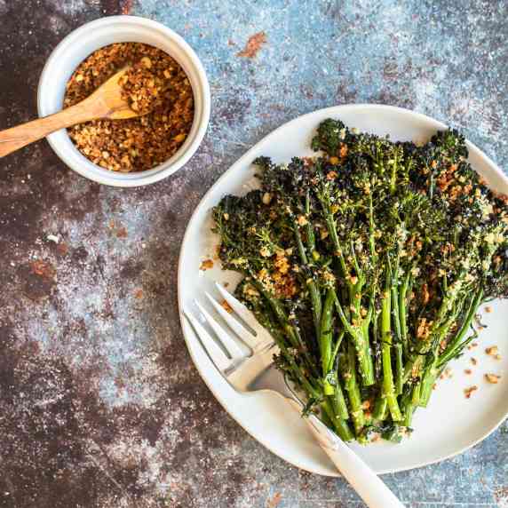 roasted broccolini on a plate topped with pine nut-enriched breadcrumbs