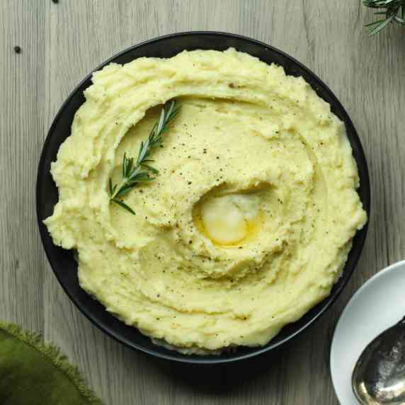 A black bowl filled with rosemary garlic mashed potatoes.