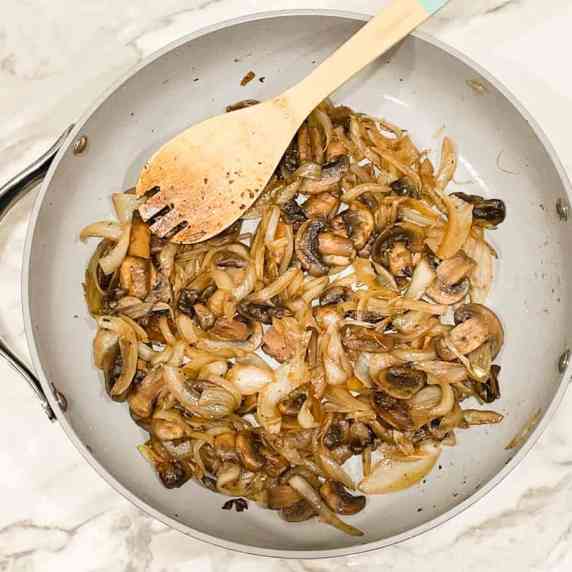 sauteed button mushrooms and onions in a pan
