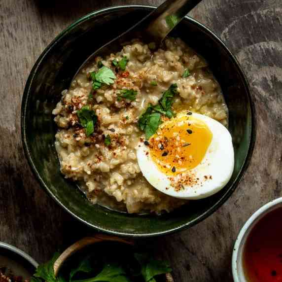 Closeup of savory oatmeal served with a soft boiled egg.