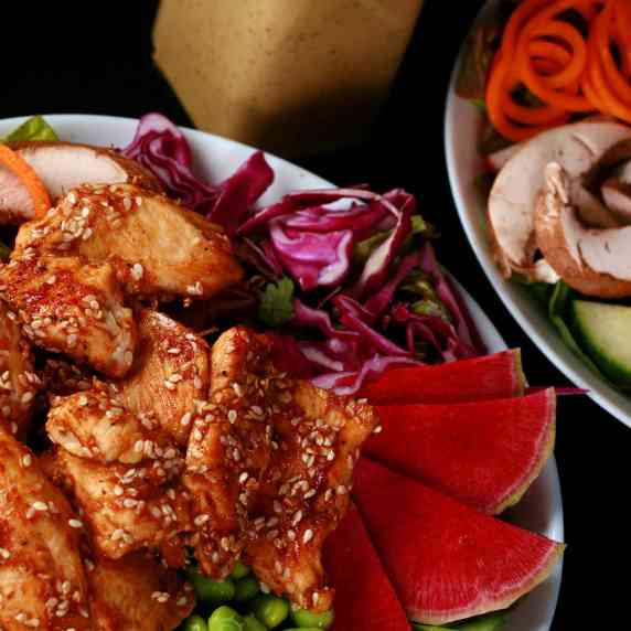 Two bowls of sesame ginger chicken salad with peanut dressing.
