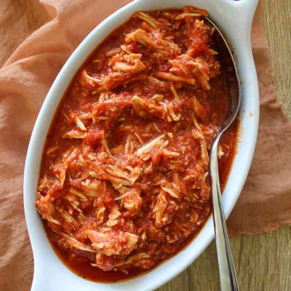 A dish of shredded chicken parmesan in tomato sauce