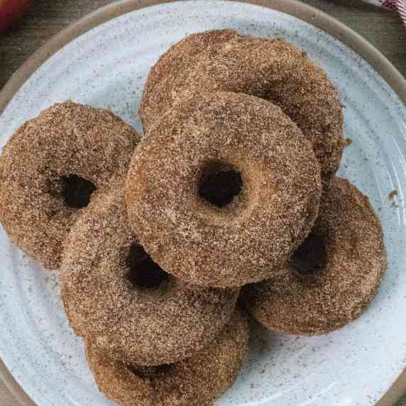 Cinnamon sugar baked donuts piled on a white and brown plate