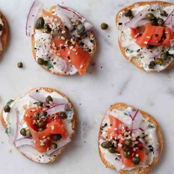 A platter of canapes with smoked salmon, cream cheese, capers, onions, and everything bagel.