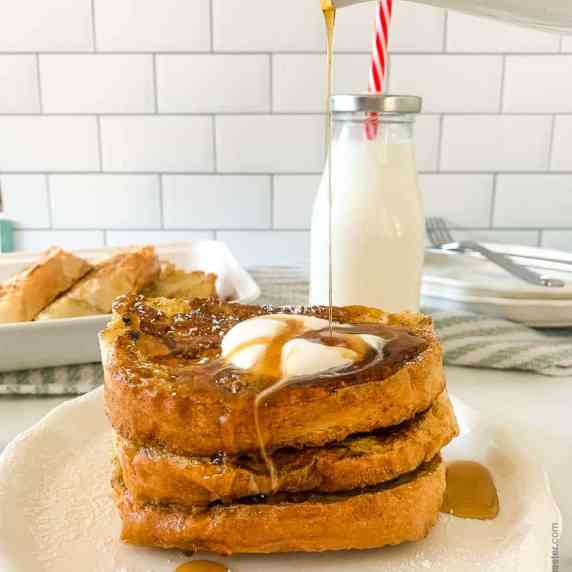 A plate of french toast pouring sauce on top