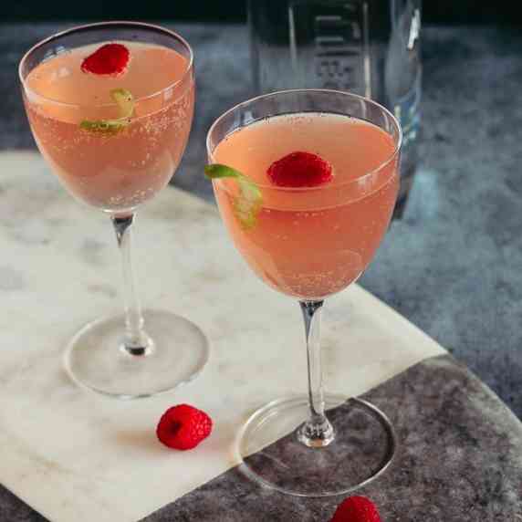 two couple cocktail glasses with sparkling raspberry tequila cocktails 