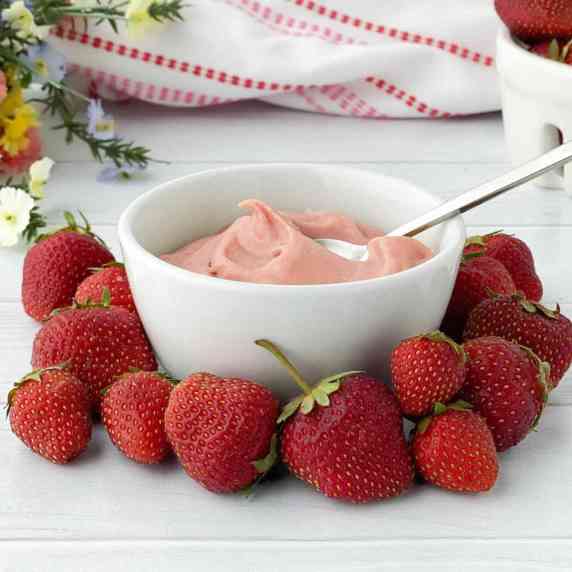 White bowl of Strawberry Pastry Cream surrounded by fresh strawberries.