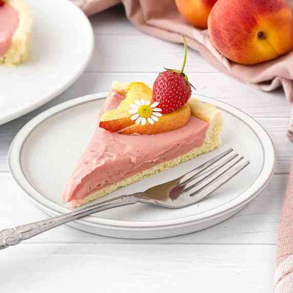 Slice of Strawberry Peach Tart on a white plate with a silver fork alongside.