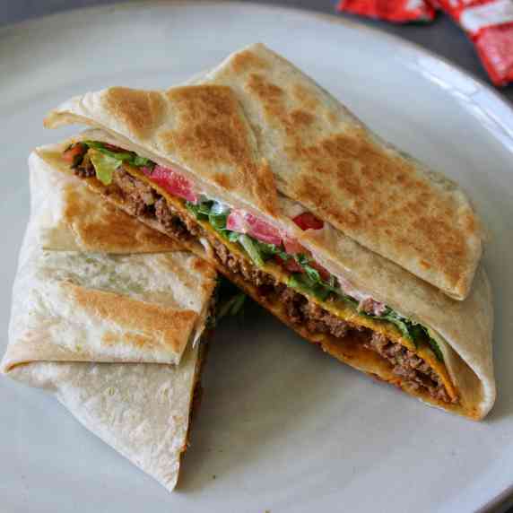 A homemade Taco Bell crunchwrap supreme, cut in half on a plate