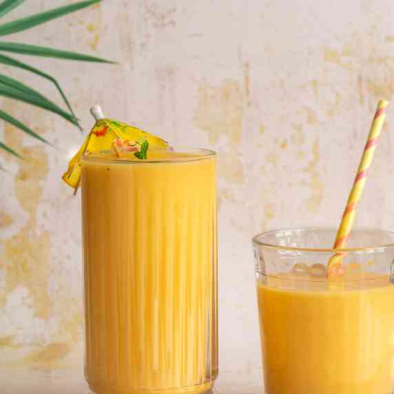 two clear glasses filled with yellow-orange coloured smoothie