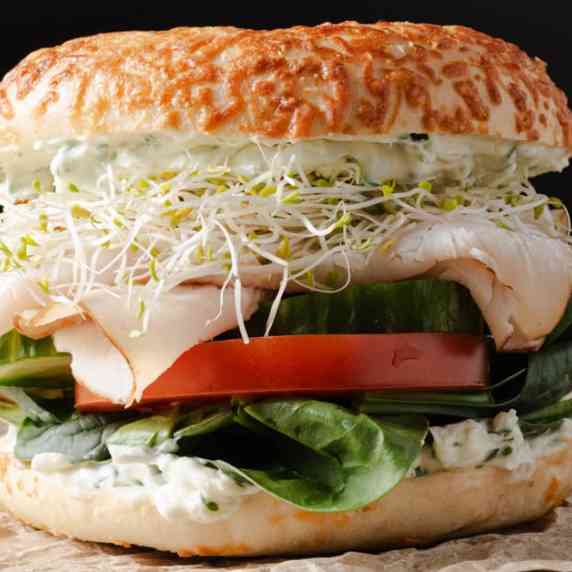 An asiago turkey bagel sandwich with chive cream cheese, and vegetables.