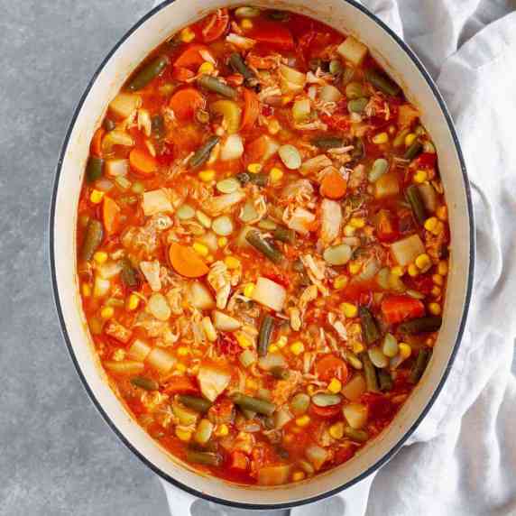 A large, oval dutch oven filled with turkey vegetable soup made with leftover turkey and veggies.