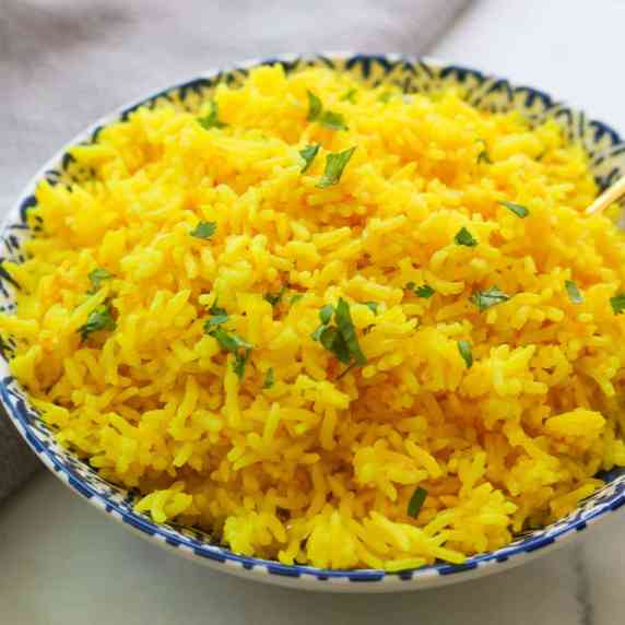 Bowl of yellow rice garnished with cilantro.