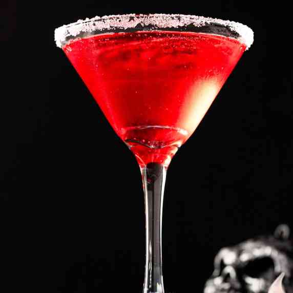 A red vampire’s kiss cocktail on a black background.