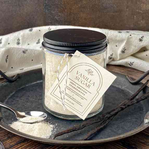 Jar of Homemade Vanilla Sugar on a metal tray with vanilla beans.