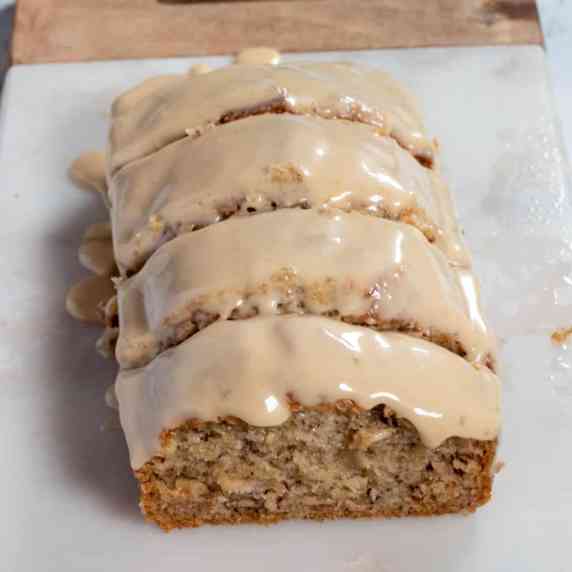 A shot showing a soft, fluffy vegan banana loaf cake, topped with a thick Biscoff glaze. 