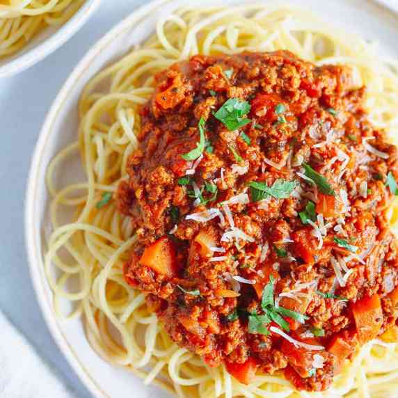 vegan bolognese with spaghetti on a creamy plate on a white countertop 