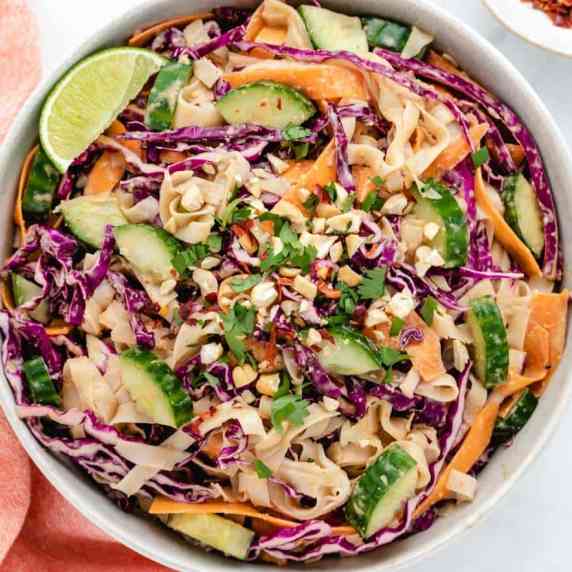 Vegan peanut noodles with carrots, carrots, and red cabbage in a bowl.