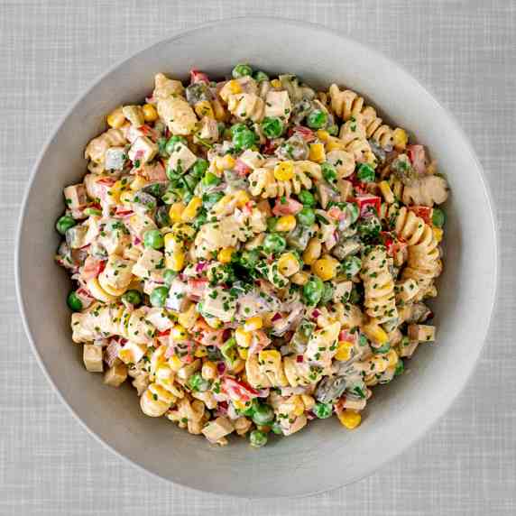 A plate filled with a colorful vegan pasta salad, seen from top