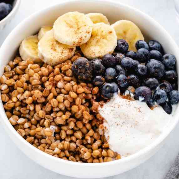 Wheat berry breakfast bowl with bananas, blueberries, and yogurt.