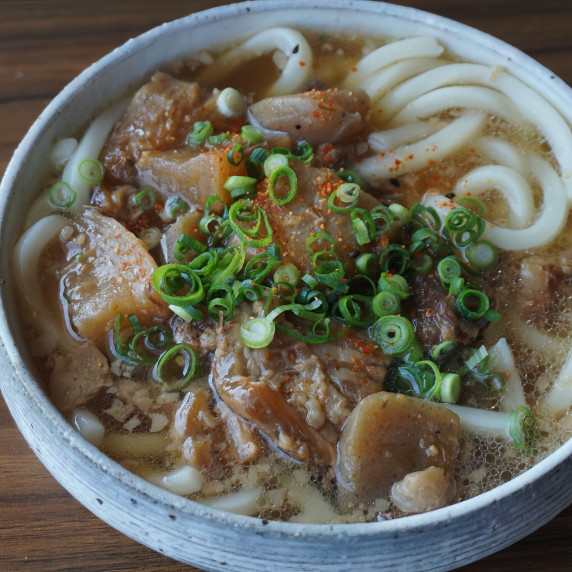 A generous serving of beef tendon and konnyaku stew is served on top of udon noodles.