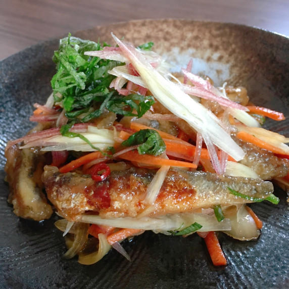 A dish of fried small sardines and then marinated with vineger and vegetables.