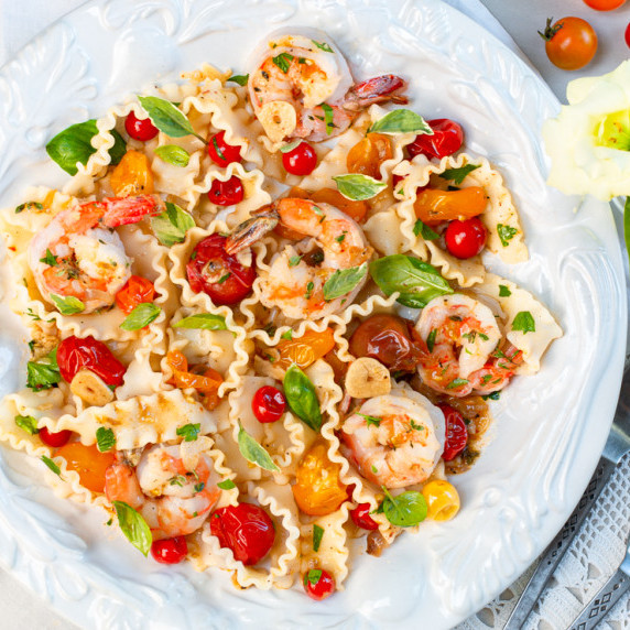 Burst Heirloom Cherry Tomatoes with Shrimp and Mafaldine Pasta in a vintage bowl with fresh basil.