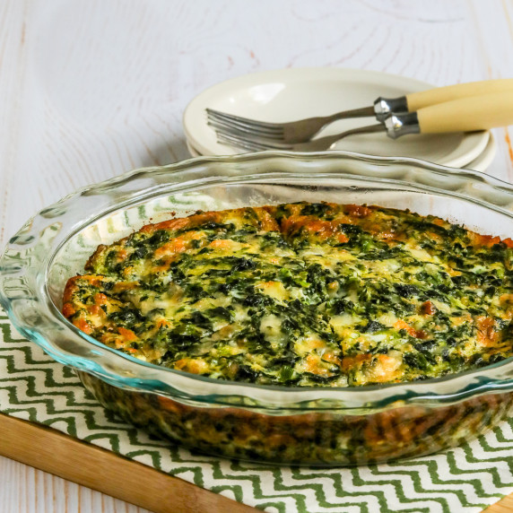 Crustless Spinach Quiche shown in baking dish with plates/forks in back.