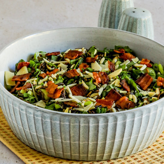 Wild Rice Salad with Bacon and Arugula shown in serving bowl with salt-pepper in back.