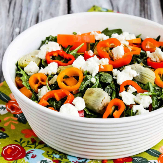 Arugula Salad with Goat Cheese, Artichokes, and Peppers shown in serving bowl on flowery napking.