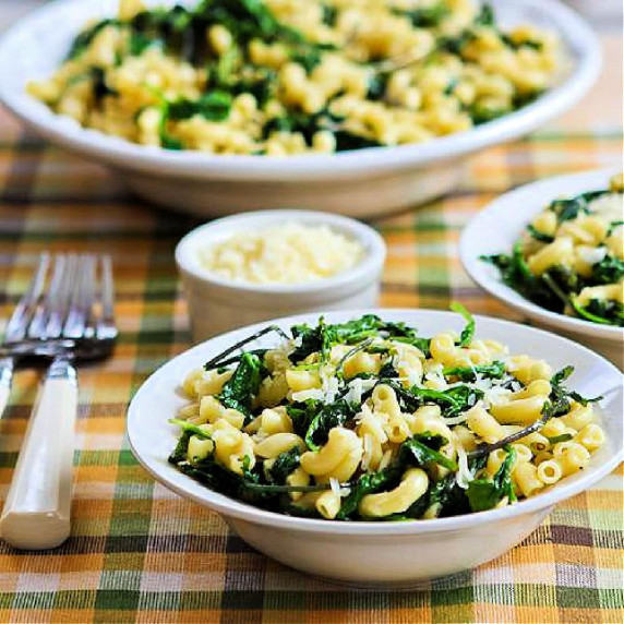 Lemon Parmesan Pasta with Greens in large serving bowl with two servings in front and Parmesan.