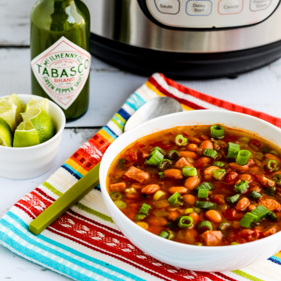Instant Pot Ham and Bean Soup in soup bowl with Instant Pot, limes, and Green Tabasco Sauce in back